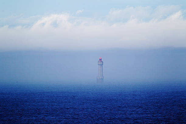 Jument lighthouse, Ushent Archipelago, emerging from sea fog. The Jumet lighthouse, NW France, guards one of the many rocky islets on the shallow, tidal waters of the Ushent Archipelago, an area of many historical shipwrecks. jument stock pictures, royalty-free photos & images