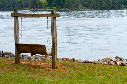 An inviting wooden swing along the shoreline of Lake Murray in the midlands of South Carolina on an overcast day.
