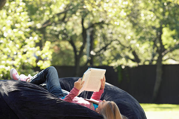 ragazza rilassante con un libro - outdoors looking at camera little girls child foto e immagini stock