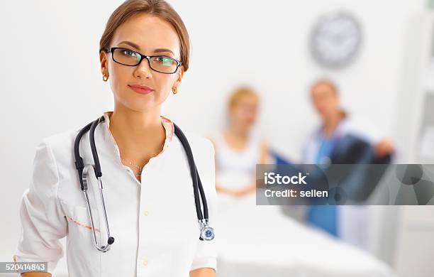 Woman Doctor Smiling And Looking To The Camera While A Stock Photo - Download Image Now