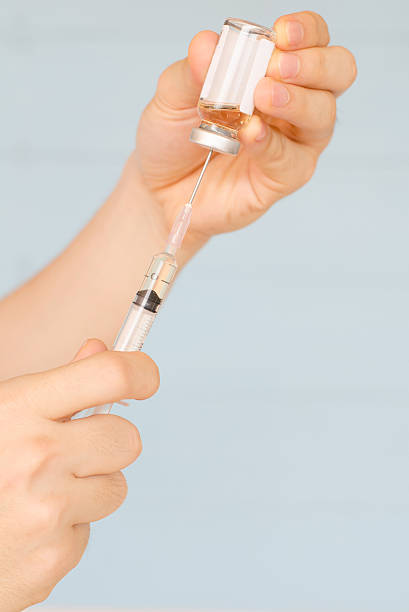 istock Nurse prepares to draw medication from glass vial 520417154
