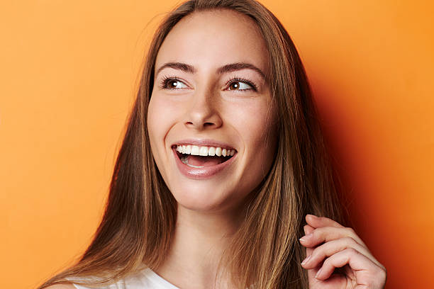 istock Smiling young woman in orange studio 520417510