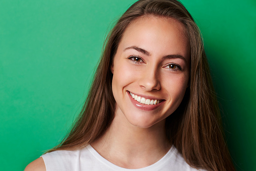 Young smiling brunette against green background
