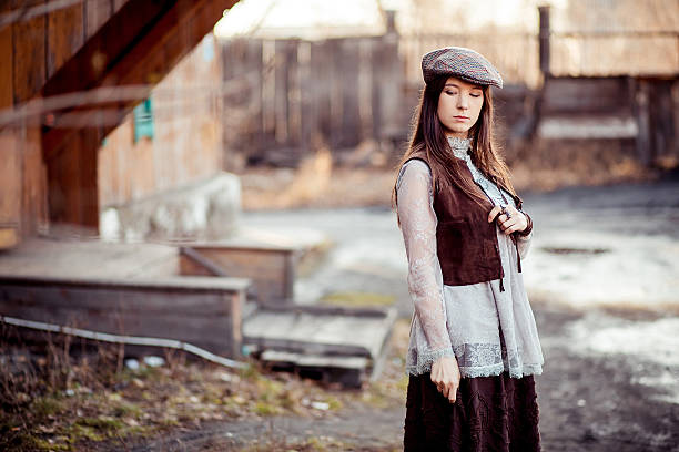 Girl in old fashioned outfit wearing flat cap at courtyard stock photo