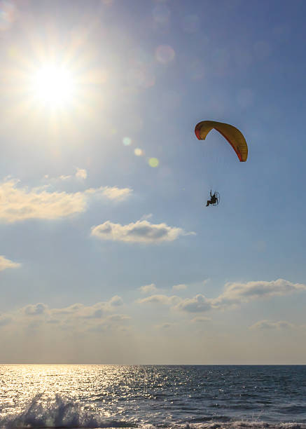 istock parachute jumper on motorized parachute flying over the sea 520420360