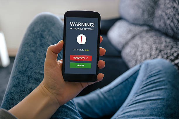 istock Girl holding smartphone with virus alert on screen 520421378