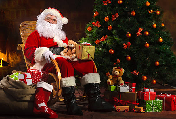 istock Santa Claus sitting in front of fireplace 520421612
