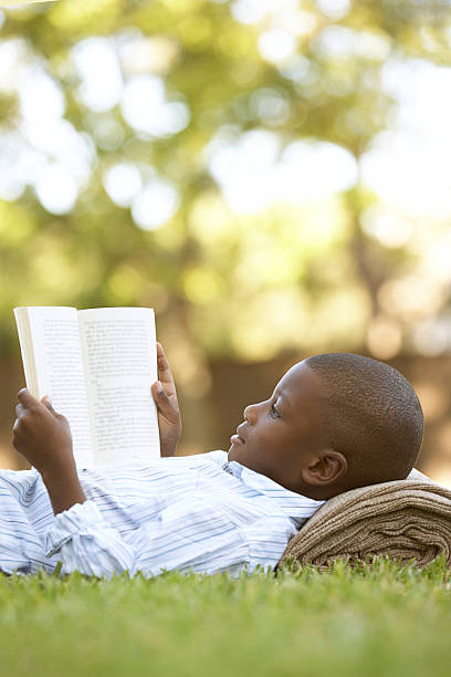 ragazzo lettura all'aperto - grass family vertical simplicity plant foto e immagini stock