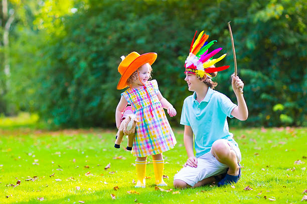 Group of happy kids with a female party animator laughing and playing with toys in park looking at camera.