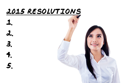 Beautiful businesswoman writes resolutions list in 2015