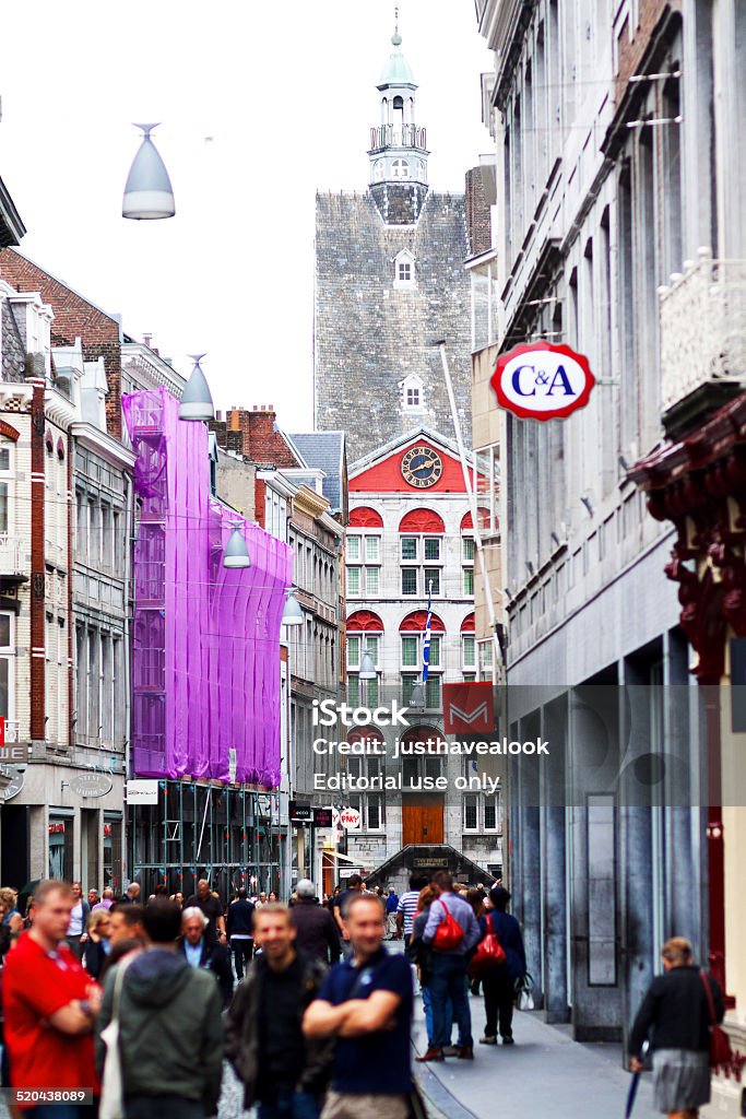 People in historical part of Maastricht Maastricht, The Netherlands - September 18, 2014: Capture of people in historical part of Maastricht. At both sides are buildings with shops. In background is old medieval building with tourist information inside. Architecture Stock Photo