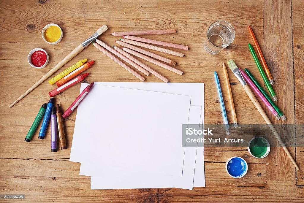 Creativity takes courage Blank paper with painting supplies and pencils on a wooden table Table Stock Photo