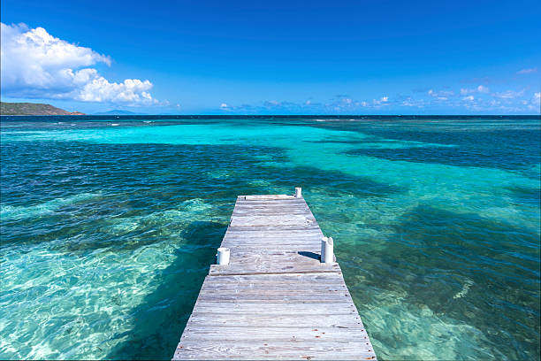 Caribbean life Rustic wooden dock extends into clear shallow lagoon at Playa Larga beach on Caribbean island of Isla Culebra in Puerto Rico culebra island photos stock pictures, royalty-free photos & images