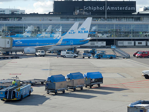Amsterdam, Netherlands - October 6, 2012: KLM plane being loaded at Schiphol Airport, Amsterdam, Netherlands. On the terrace of the airport, passengers wait for their flight. On the track, along with the aircraft operators work carrying suitcases and maintenance of aircraft. There are 163 destinations served by KLM, many are located in the Americas, Asia and Africa