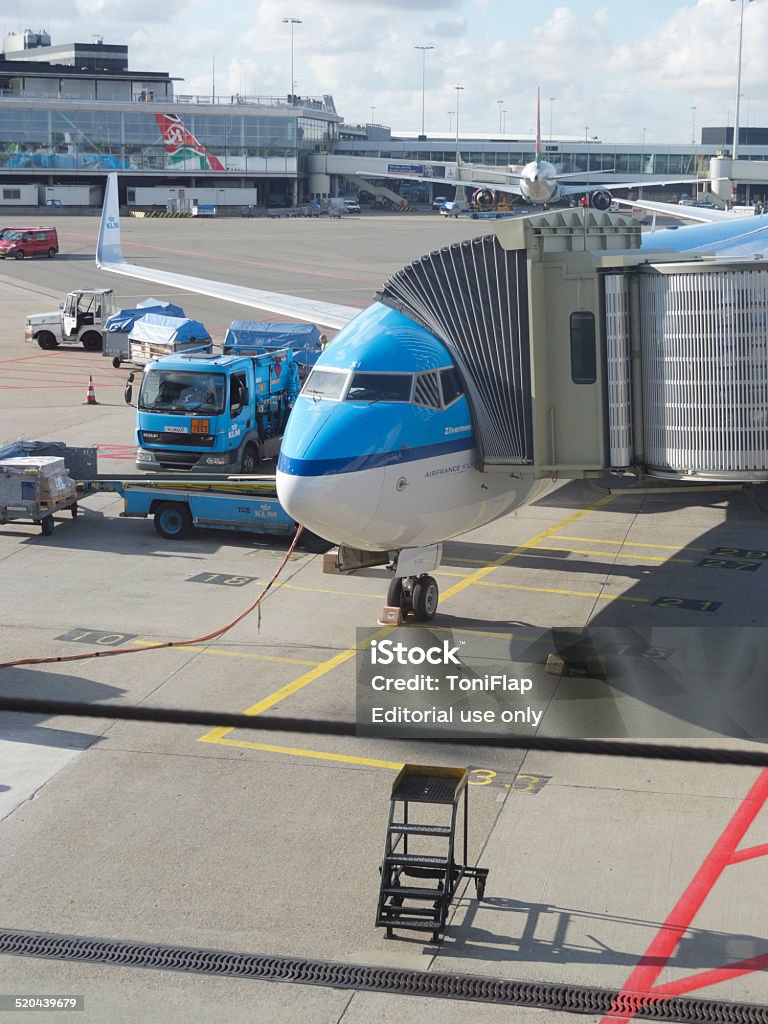 LM plane being loaded at Schiphol Airport Amsterdam, Netherlands - October 6, 2012: KLM plane being loaded at Schiphol Airport, Amsterdam, Netherlands. On the terrace of the airport, passengers wait for their flight. On the track, along with the aircraft operators work carrying suitcases and maintenance of aircraft. There are 163 destinations served by KLM, many are located in the Americas, Asia and Africa Aerospace Industry Stock Photo