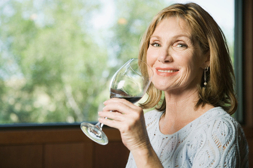 Mature woman drinking wine and smiling, portrait