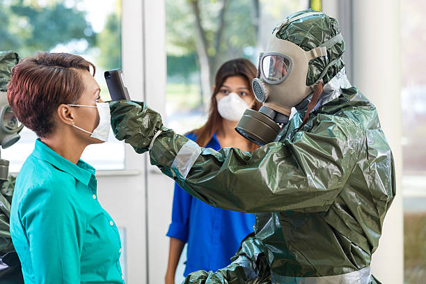 Doctor in hazmat suit examining woman during contagious outbreak Businesspeople wearing protective masks while hazmat team examines office ebola stock pictures, royalty-free photos & images