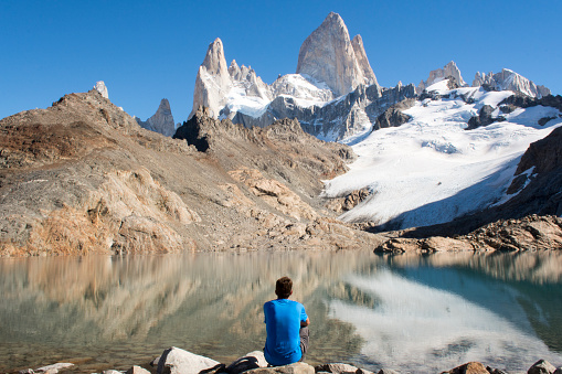 Man sitting down at Lago de Los Tres in front of Cerro Fitzroy, in Los Glaciares National Park, near El Chalten in Patagonia, Argentina