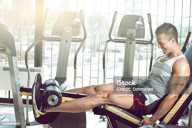 Man Doing Leg Extension In Gym Stock Photo - Download Image Now - Gym, Men, Sports Training