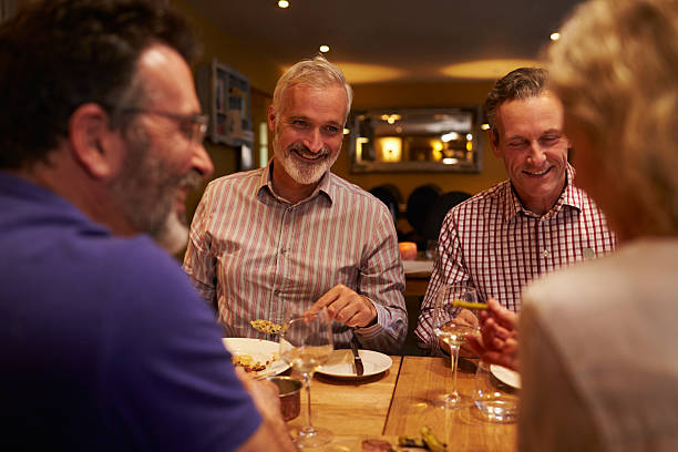 quatre amis discutant ensemble à l'occasion d'un repas dans un restaurant - dining senior adult friendship mature adult photos et images de collection