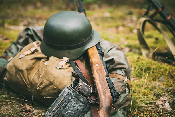 German military ammunition of World War II on ground. Military helmet, lights, rifle