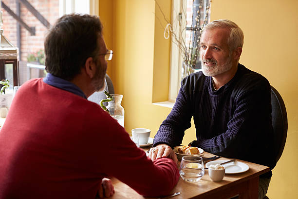 istock Male couple holding hands at restaurant, over shoulder view 520493502