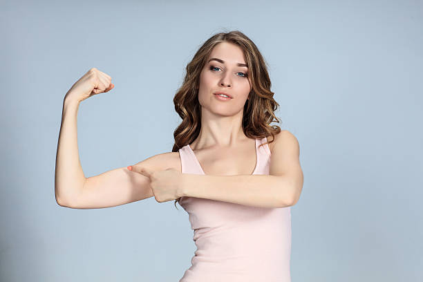 istock The young woman showing her muscles on gray background 520494348