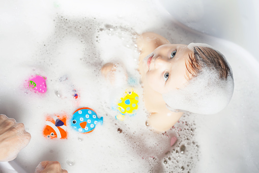 Baby wash in the bath. Playing with water toys. Use soap, shampoo for children. Baby shampoo not sting eyes