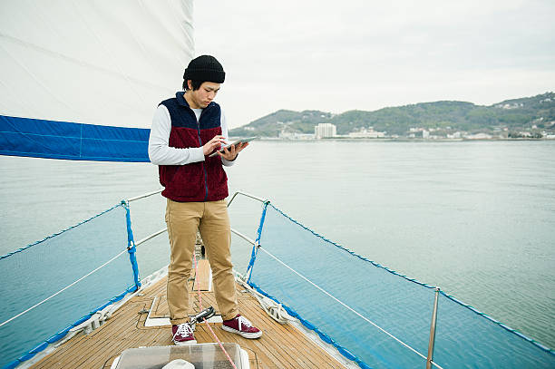 junger mann mit digitaltablett auf der jacht - recreational boat aspirations discovery yacht stock-fotos und bilder