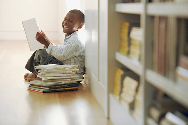 Young boy laughs at a storybook Young boy laughs at a storybook reading comic book stock pictures, royalty-free photos & images