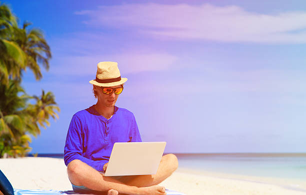 istock man with laptop on tropical beach 520498764