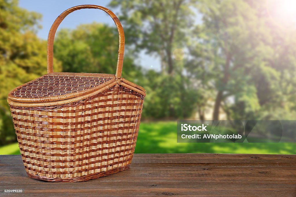 Picnic Basket Or Hamper On  Wooden Bench In Garden Closed Picnic Basket Or Hamper On  The Brown Rustic Wooden Table Or Bench In Park Or Garden Front View, Copy Space Picnic Table Stock Photo