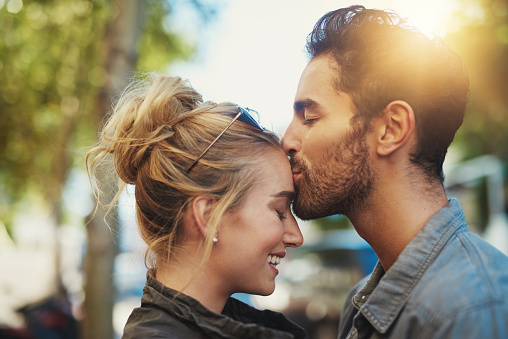 Wedding Couple in Love looking at each other side view. Romantic Bride and Groom Happy embracing. Smiling Elegant Man and Lady over Gray Studio Background