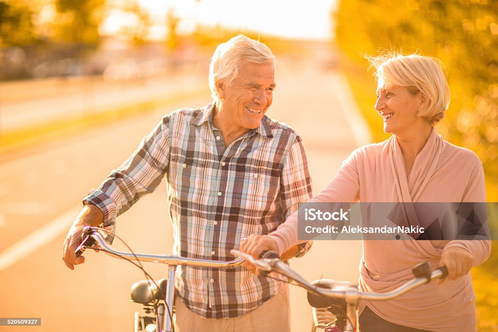 Loving senior couple Portrait of a loving senior couple pushing bikes outdoors 50-59 Years Stock Photo