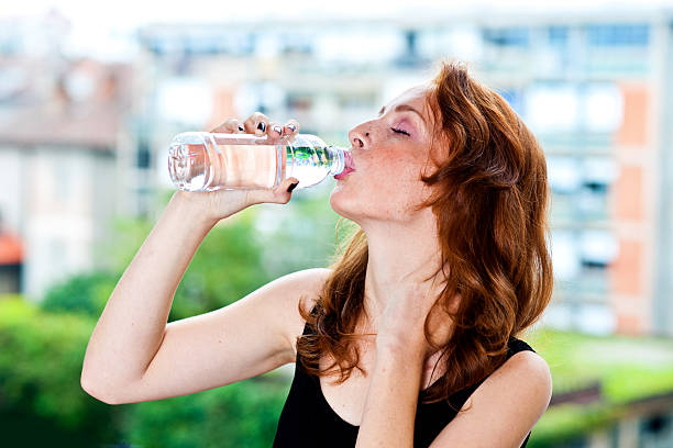 istock freckled woman drinks water from bottle 520509627
