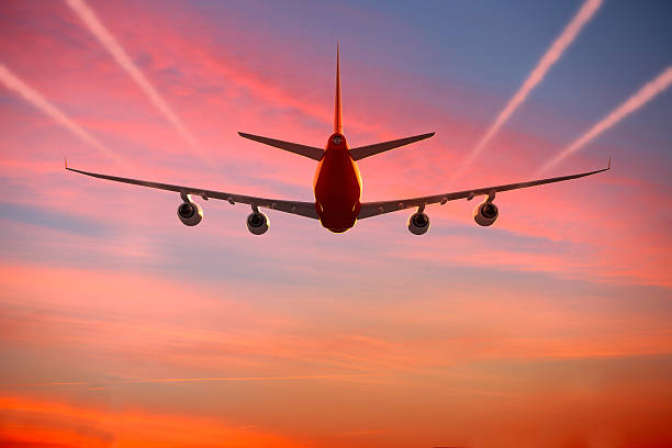 avión volando en el cielo al atardecer con senderos de vapor - wing airplane sky jet fotografías e imágenes de stock