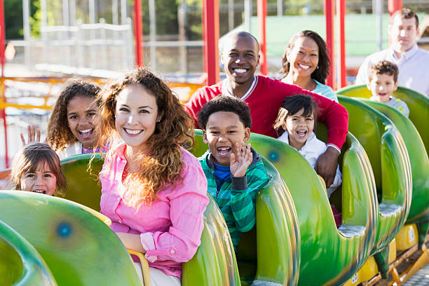 Multiracial group of people on rollercoaster ride Group of people on a rollercoaster ride at amusement park.  Focus on African American boy waving (6 years). amusement park ride photos stock pictures, royalty-free photos & images