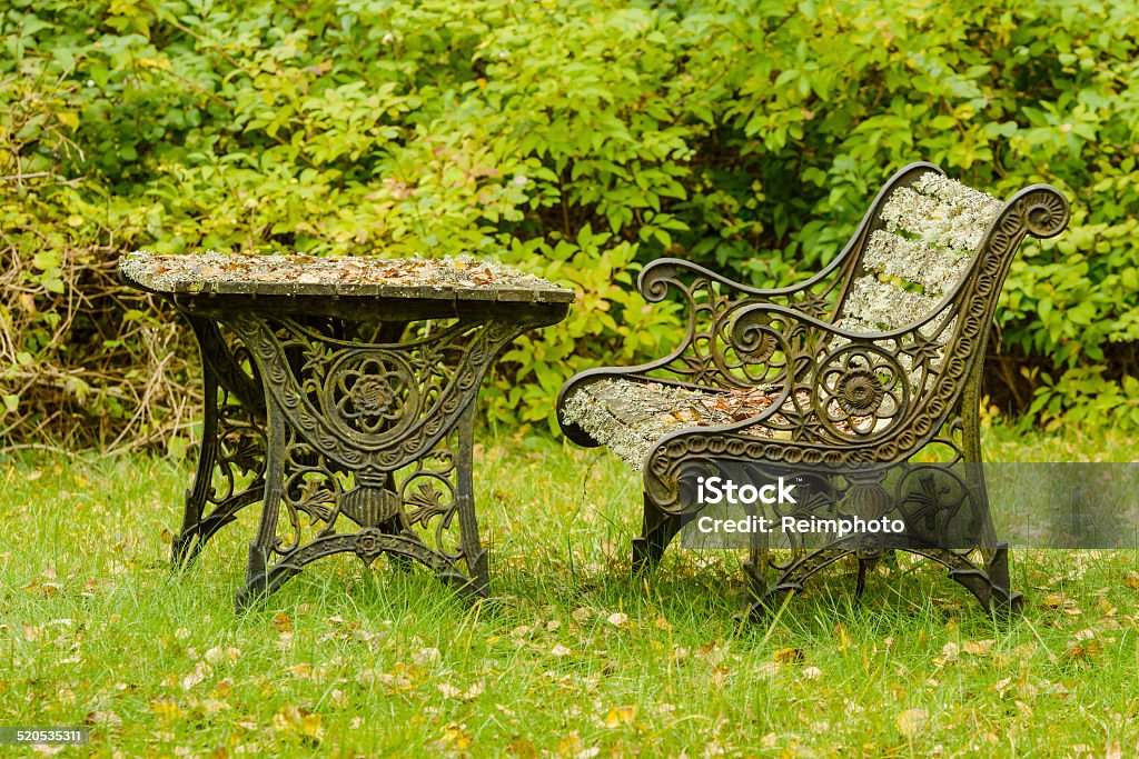 Very old furniture Very old and unused cast iron furniture in garden. Sofa and table are covered in lichen, dry leaves and twigs from years of neglect.Beautiful autumn scene. Abandoned Stock Photo
