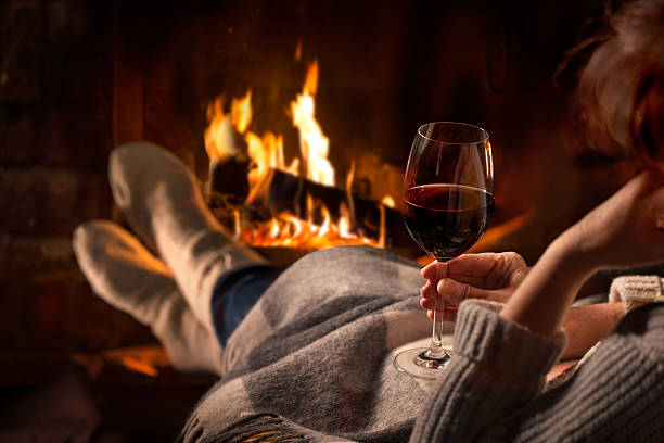 Woman resting with wine glass near fireplace Woman resting with glass of red wine near fireplace heat home interior comfortable human foot stock pictures, royalty-free photos & images
