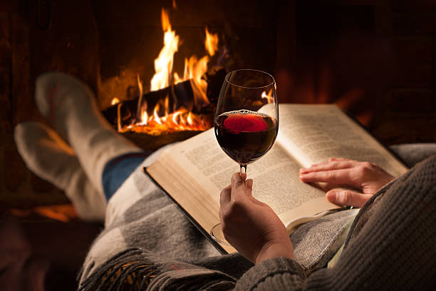 Woman reads book near fireplace