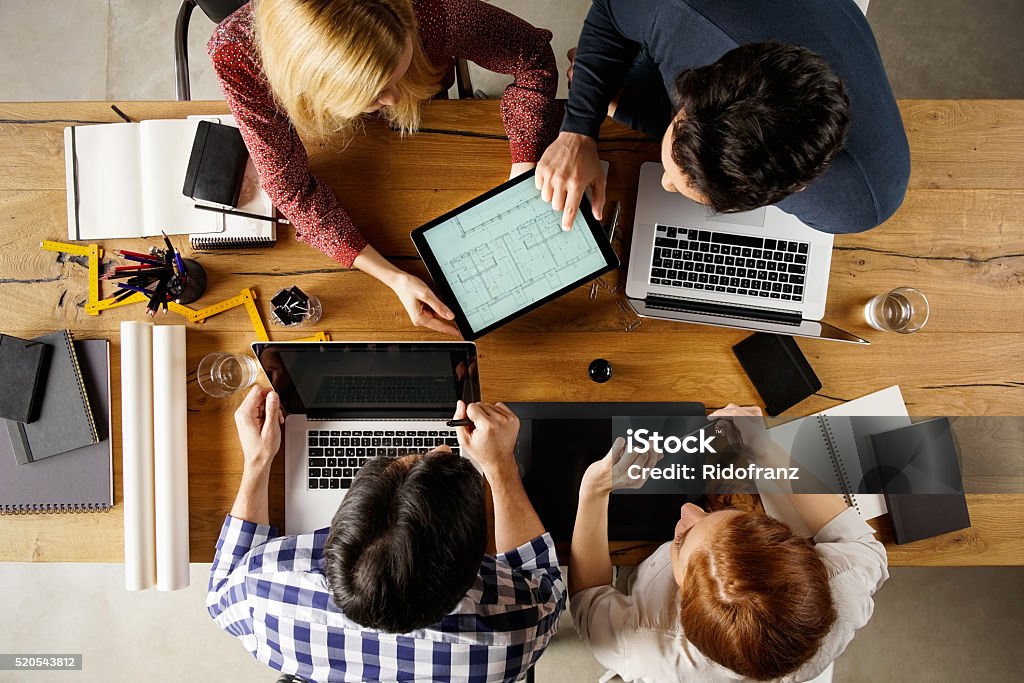 Interior designers at work High angle view of team of architecs designing layout on laptop. Architect showing project house at his colleague and working together on laptop. Top view of business people in a meeting. Architect Stock Photo