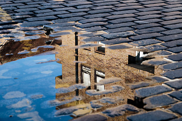 Cobblestone with reflection of house in puddle after rain