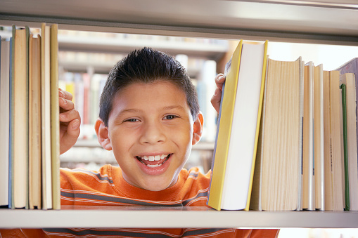 Boy smiling between books