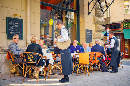 Budapest, Hungary - October 2, 2015: People sit and are being served by waiters at the patio of Central Kavehaz cafe restaurant in downtown Budapest, Hungary.