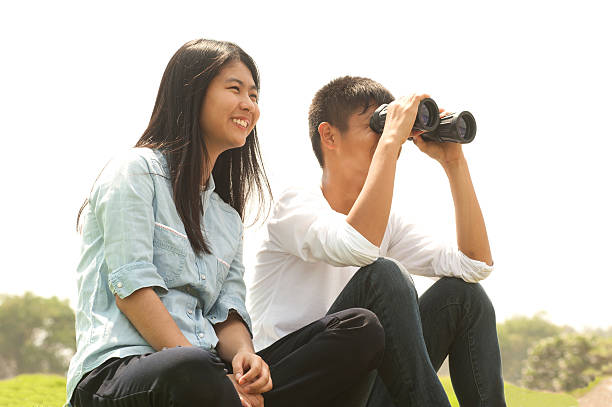 istock Young boy and girl sit on mound seeking Binoculars . 520556338