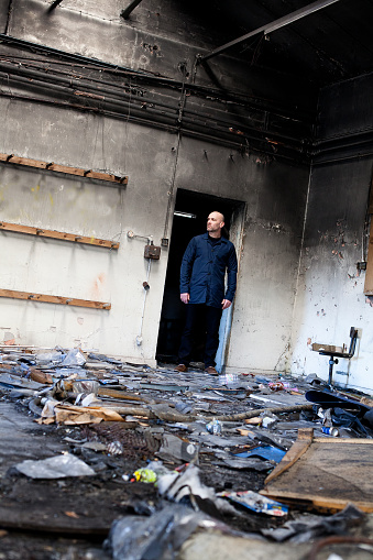 Man standing in a doorway of a derelict building with lots of debris and rubbish on the floor