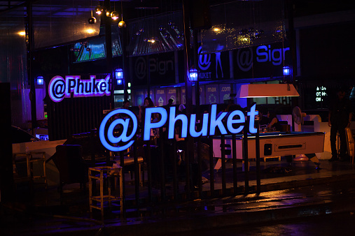 Bangkok, Thailand - October 25, 2014: Night shot of young Thai people in outside bar in street Chokchai 4 in Ladprao. Male guests are served by young thai girls. Behind neon letter name of bar a thai girl is smoking water pipe. Popular nightlife place in street.Daily scenery.