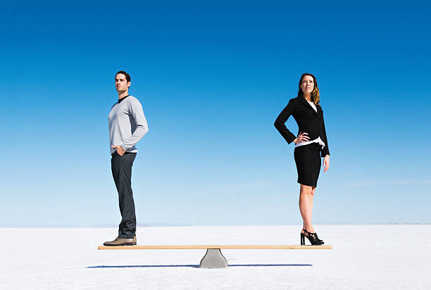 Gender equality Businesswoman and businessman balanced on Seesaw. Gender equality concept. equity vs equality stock pictures, royalty-free photos & images
