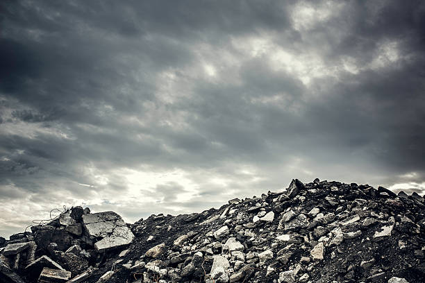 Desolate Concrete Rubble Wasteland A heaping pile of broken cement, concrete, asphalt, and building pieces lay strewn about in mounds and hills of waste, ominous gray clouds overhead.  Horizontal image with copy space.  Post apocalyptic ruins, destroyed city, or just a dump? the ruined city stock pictures, royalty-free photos & images