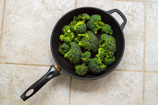 Broccoli in a dark black pan isolated on stone tile